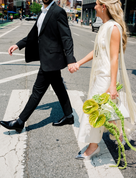 Couple crossing a New York City street after their courthouse wedding with a green anthurium bouquet
